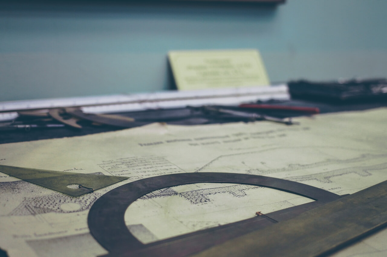 Survey plans and drafting tools on a work table